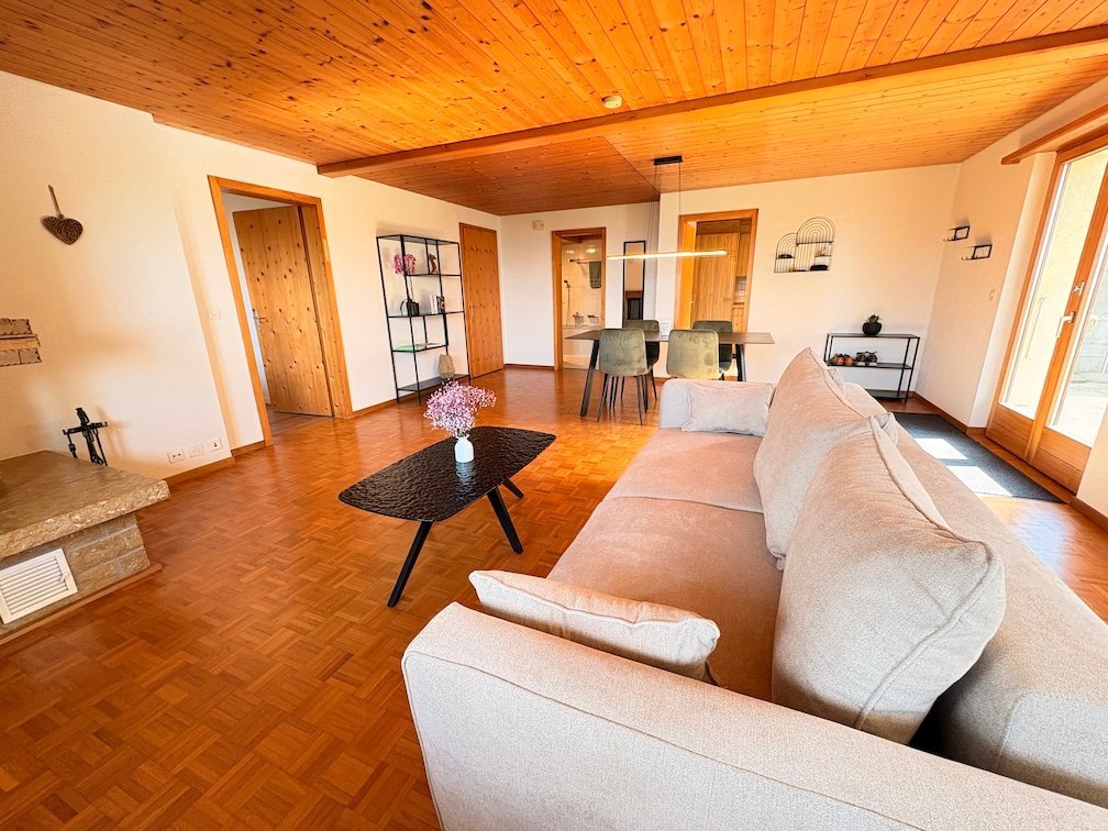 Salón luminoso con sofá, mesa de comedor y techo de madera